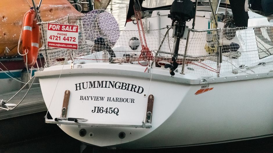 A sailboat with a 'for sale' sign at the dock