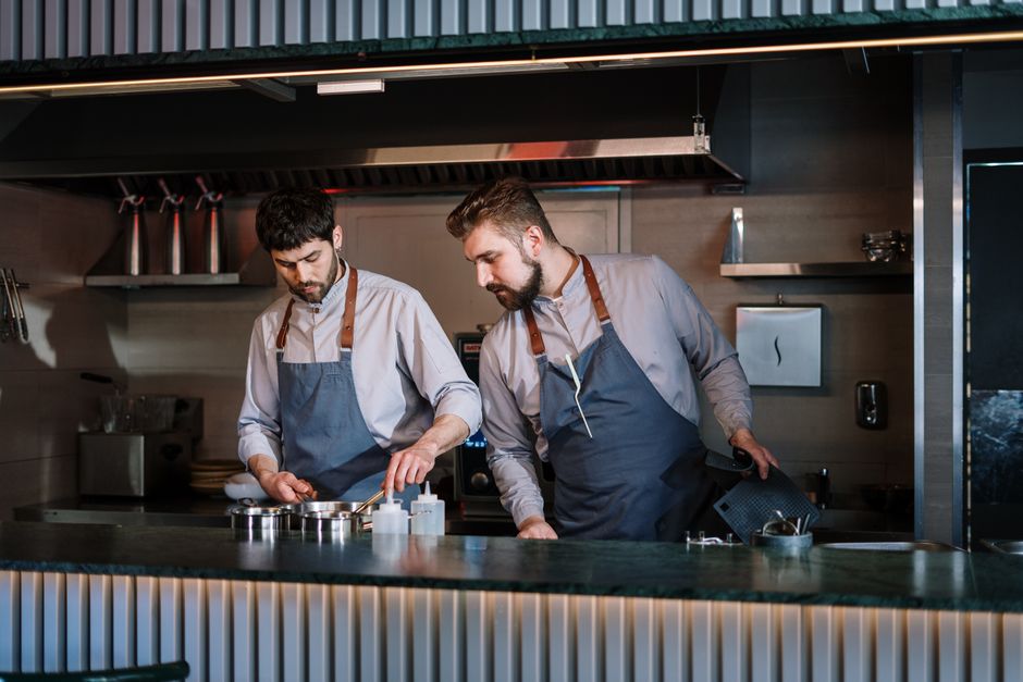 Two chefs cooking in a busy contemporary restaurant kitchen