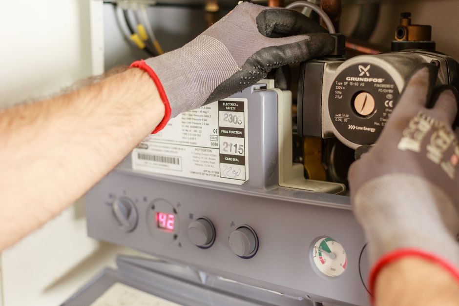 Plumber's hands adjusting a boiler system with tools