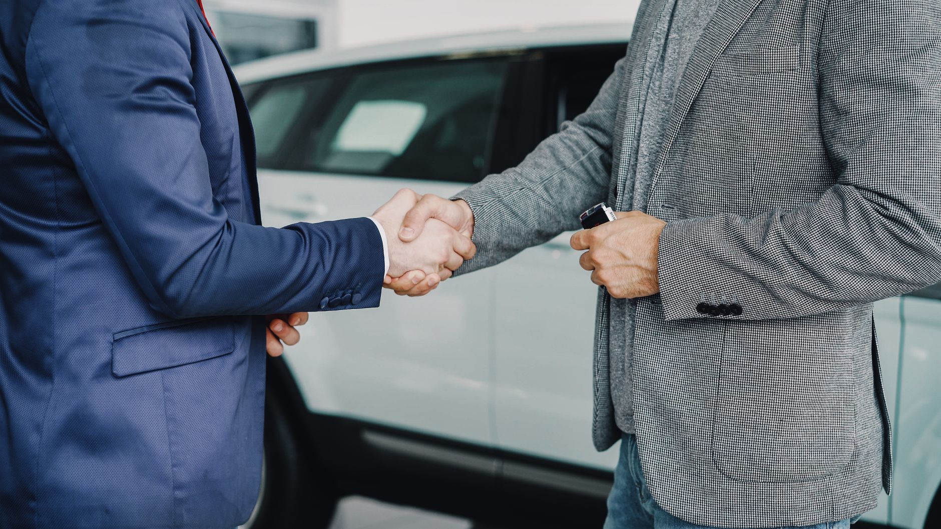 Two businessmen shaking hands in a dealership to seal a deal