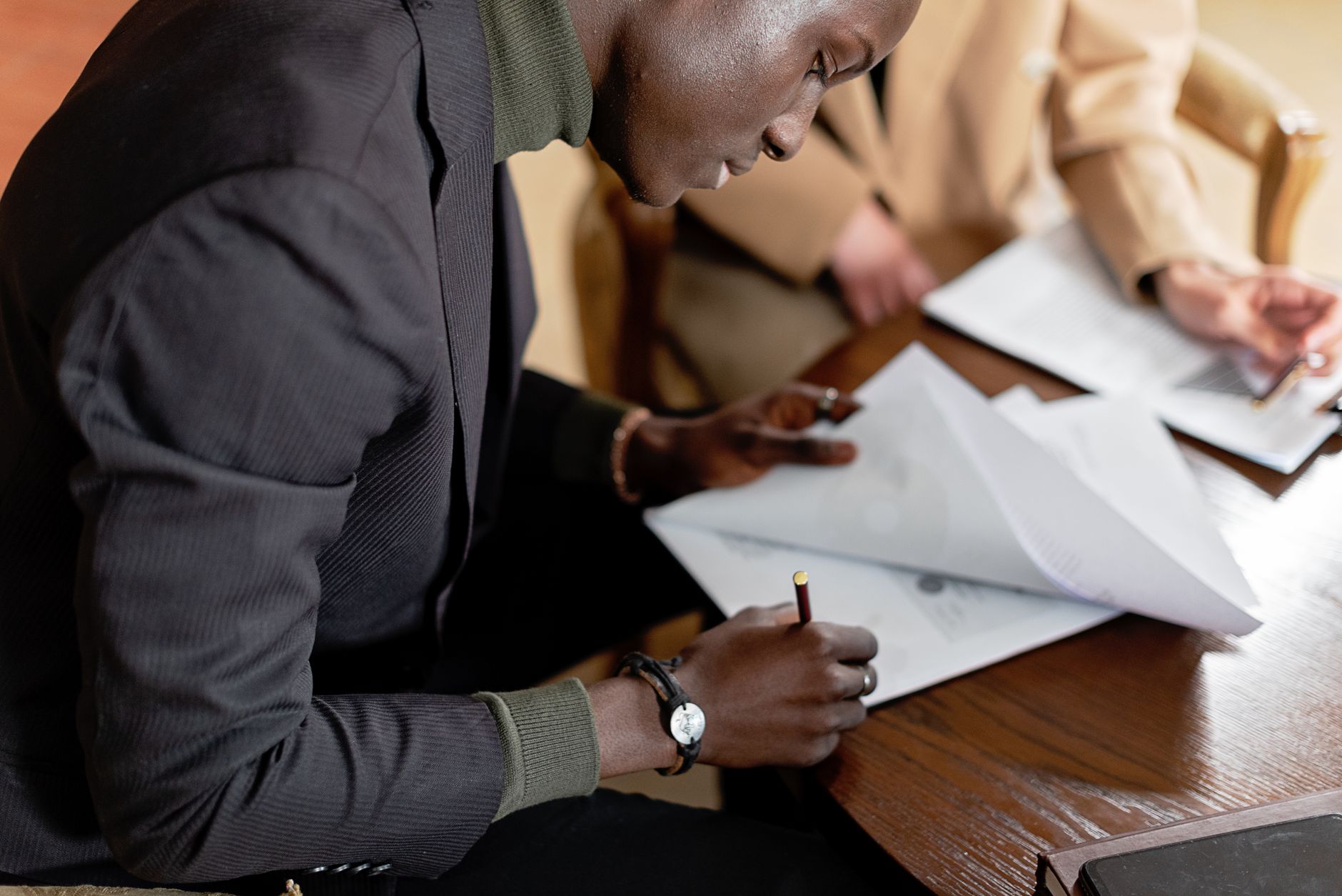 Man in a blazer signing business documents at a desk
