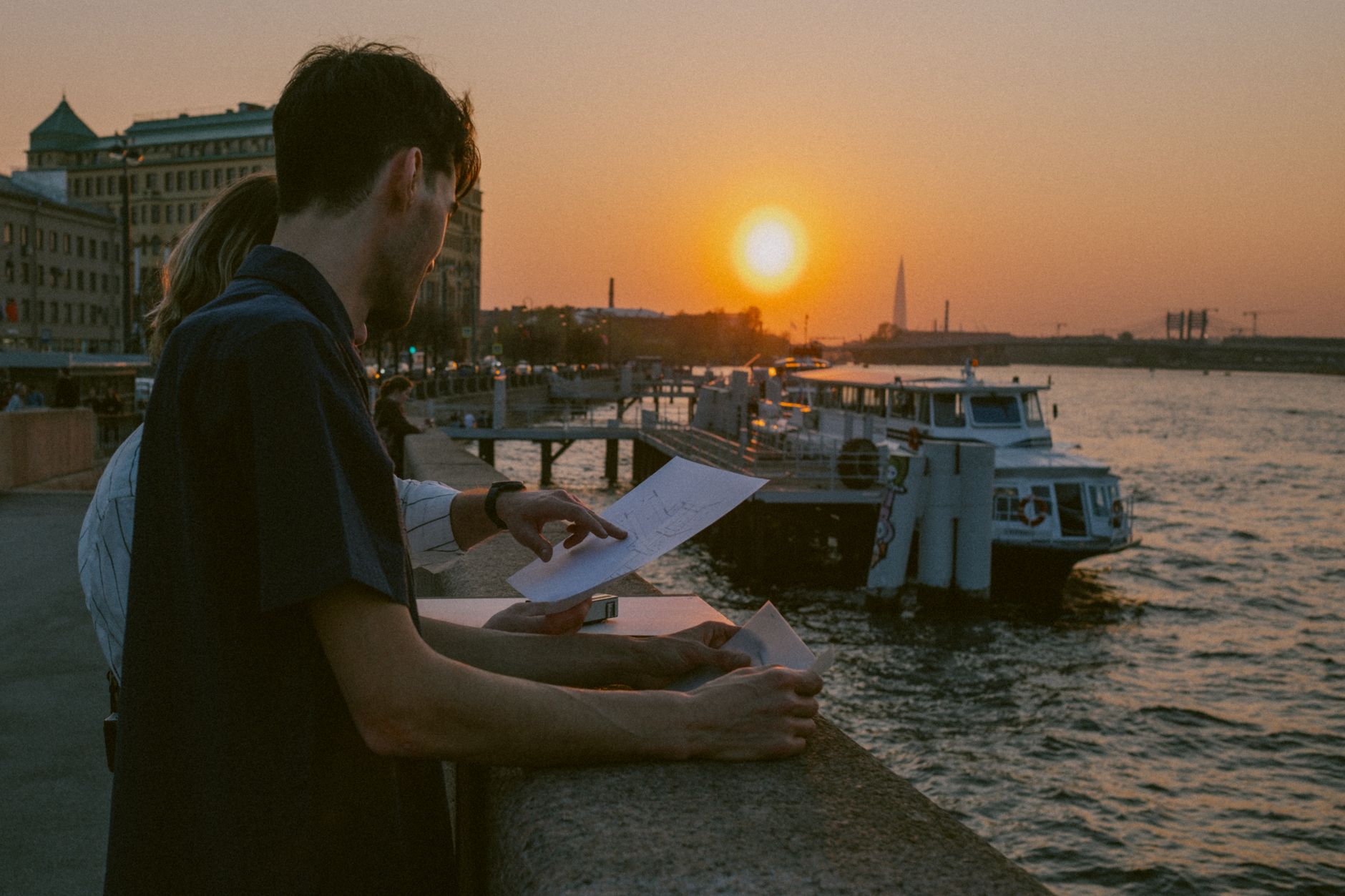 People discussing plans by the waterfront at sunset