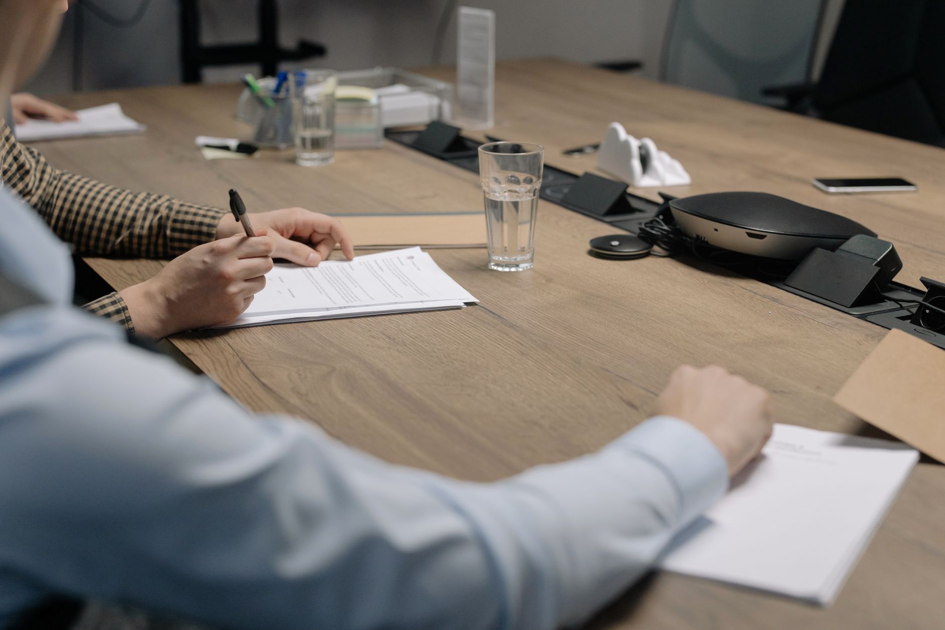 People signing documents at a conference table in a business meeting