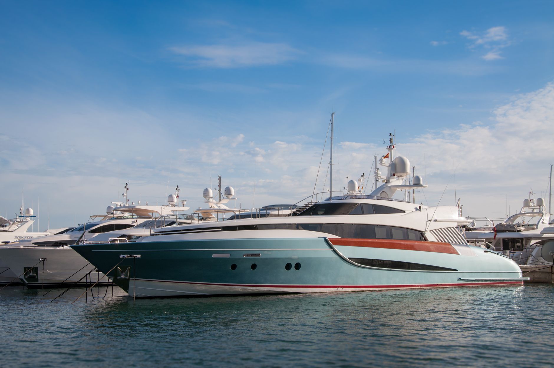 Yachts and boats docked at a marina under a blue sky
