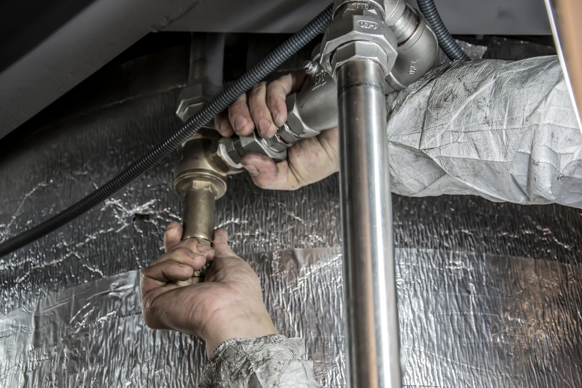 Plumber's hands installing steel pipe fittings indoors