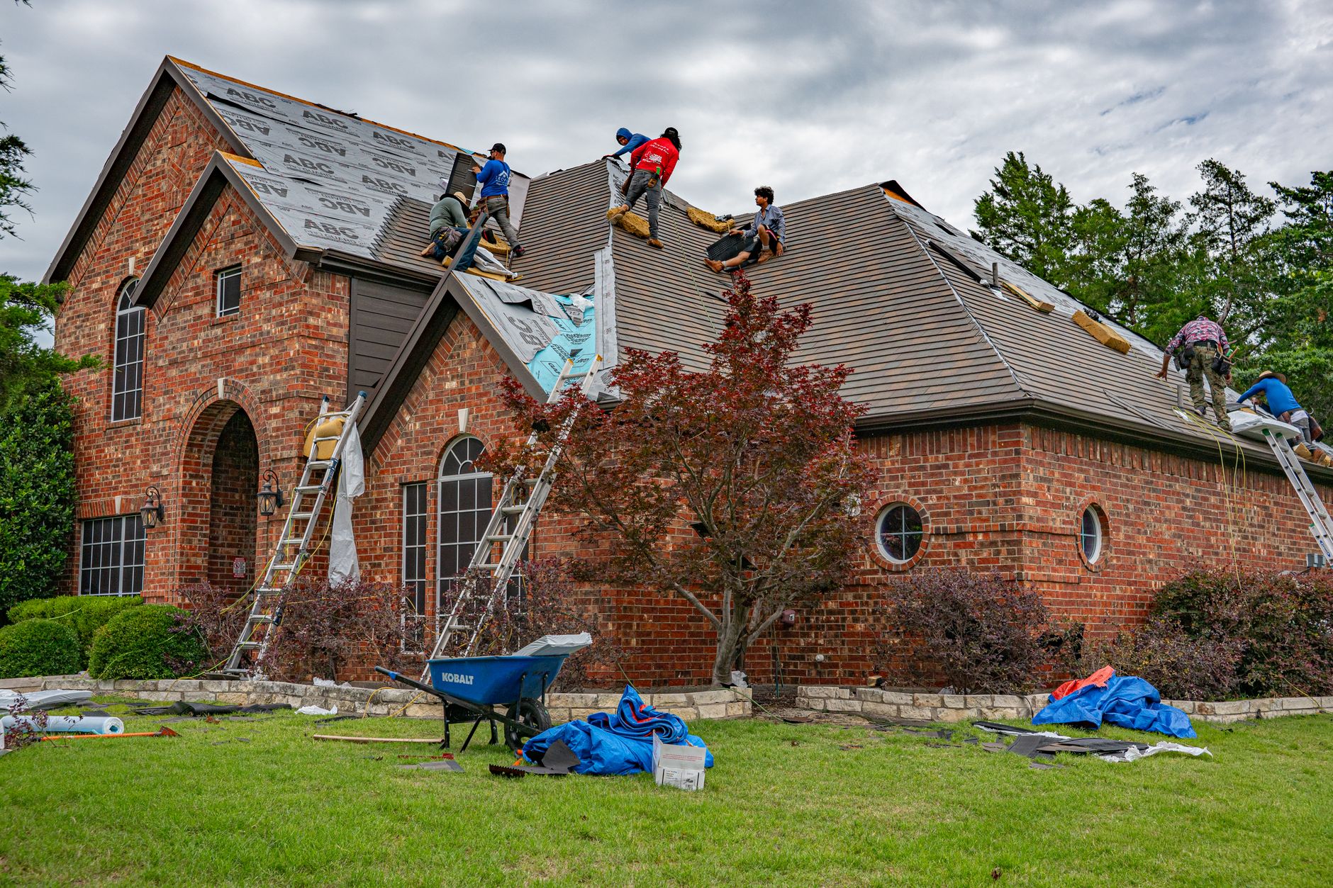 Roofers installing shingles on a brick home