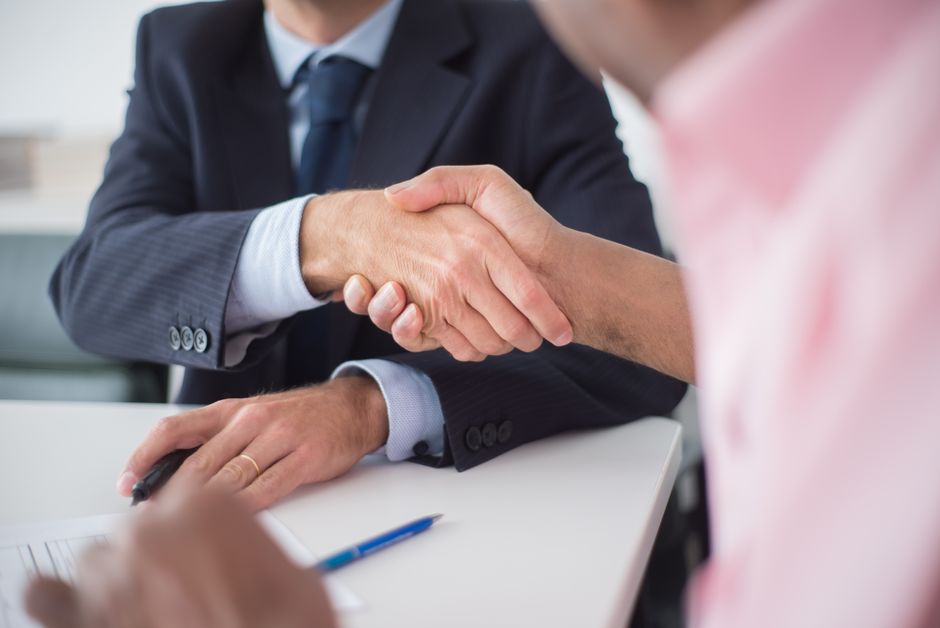 Two businesspeople shaking hands across a table